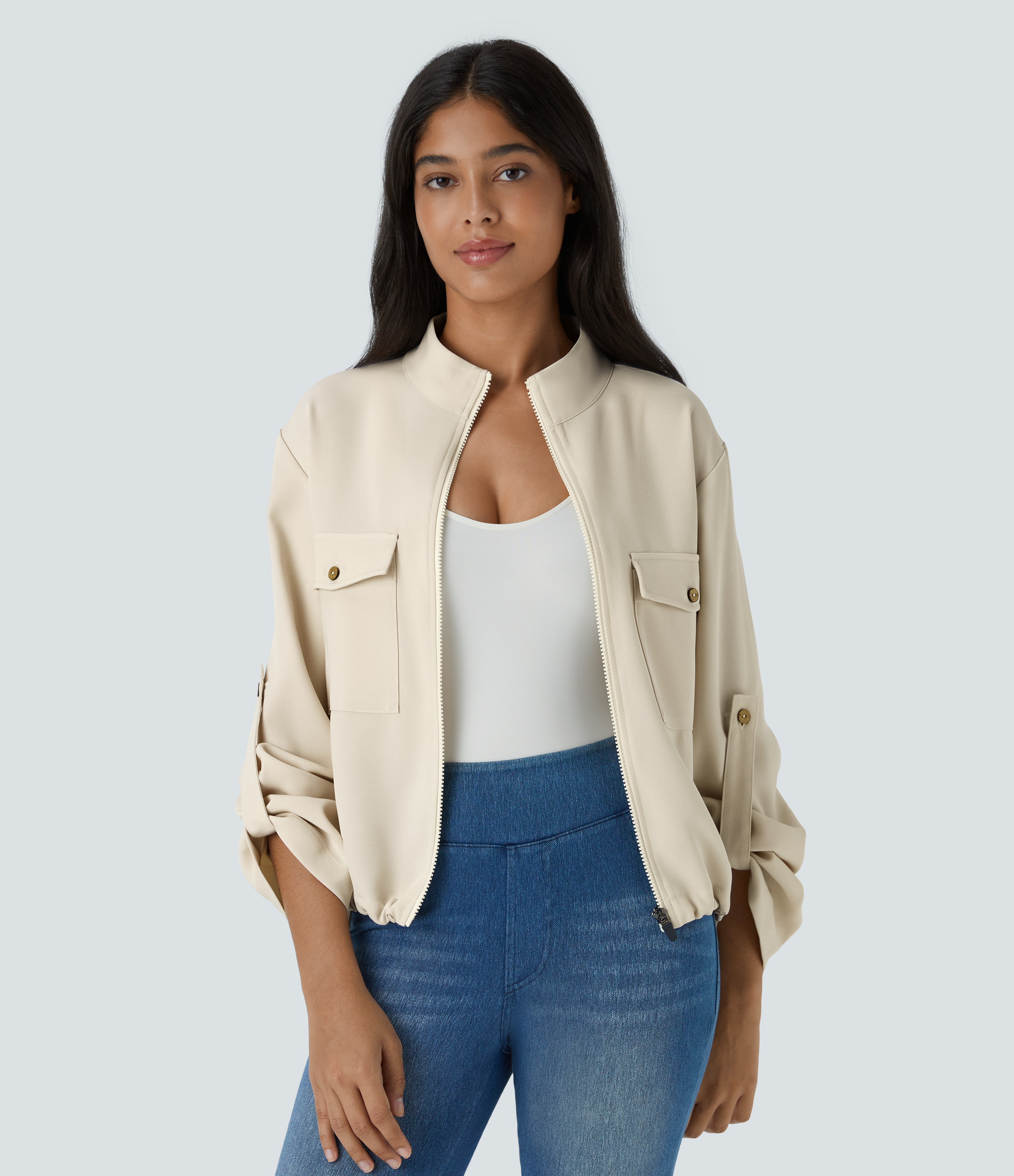 Stand collar, roll tabs on sleeves, flap pockets, drawstring closure, and zip hem. Casual jacket.