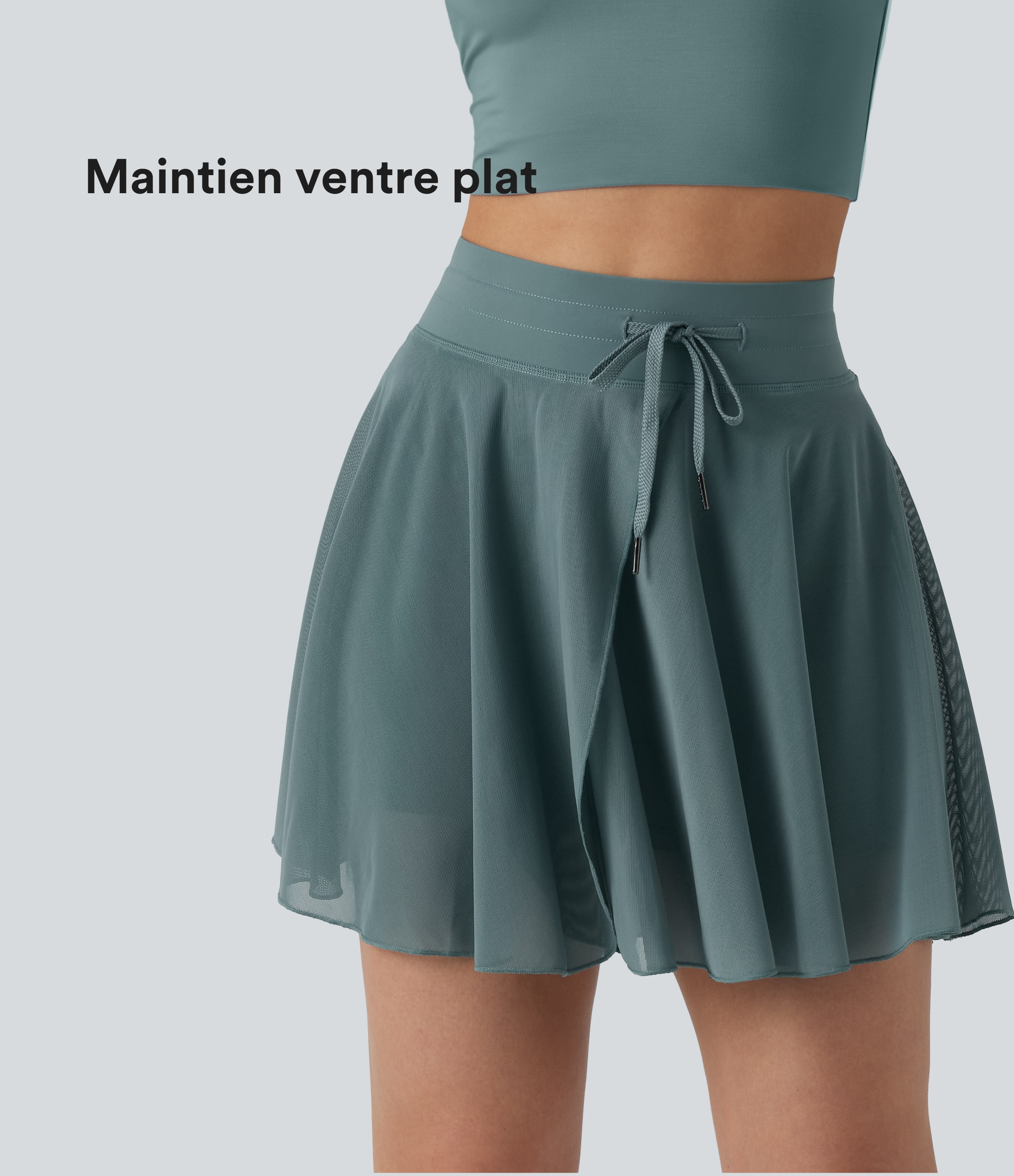 Minifalda 2 en 1 fluida con vuelo, cintura alta y cordón, paneles de malla en contraste y bolsillo; versión más larga